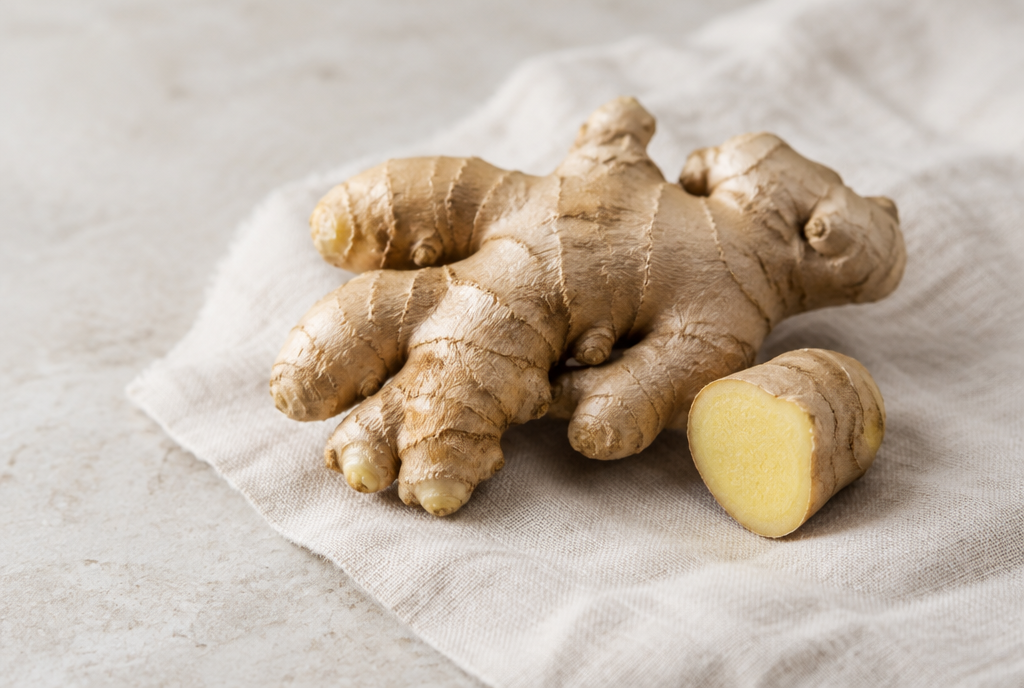 A hand of fresh ginger root with one piece cut open