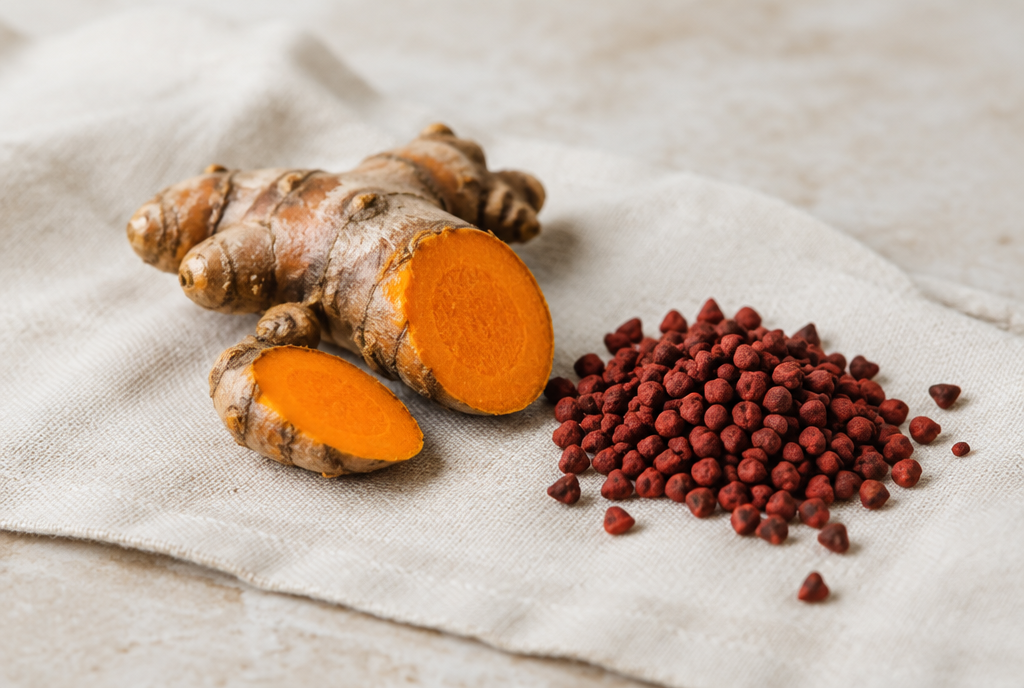 Turmeric root cut open beside red achiote seeds