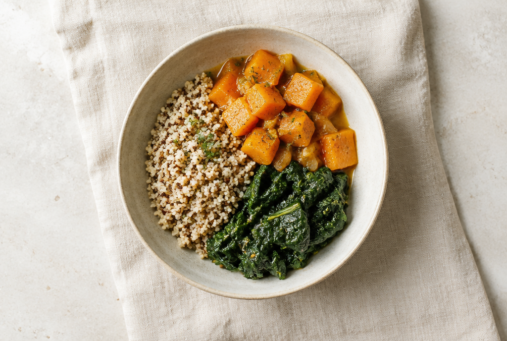 A dinner bowl of grain, stewed squash and greens from above